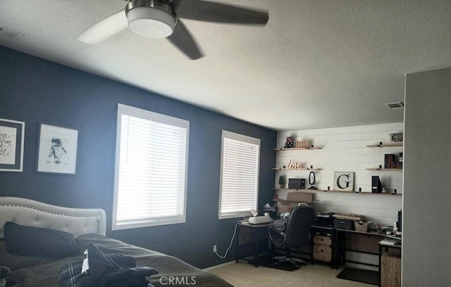 carpeted bedroom with ceiling fan and a textured ceiling