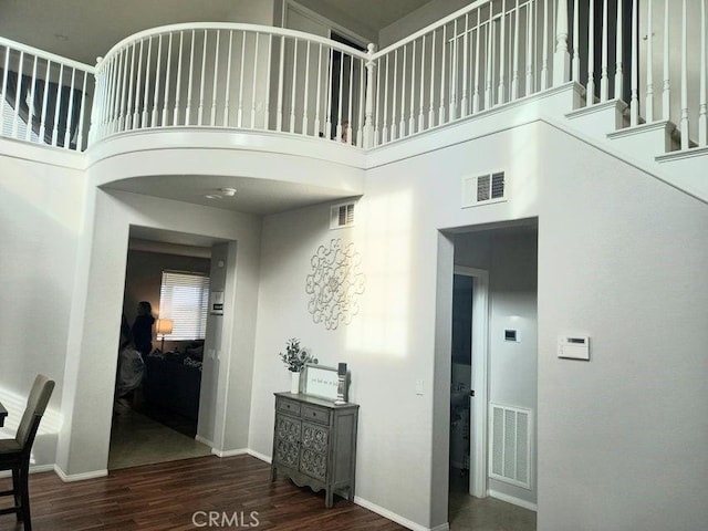 hallway featuring a towering ceiling and dark hardwood / wood-style flooring