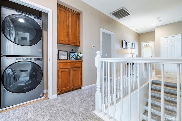 laundry room with light colored carpet and stacked washer / drying machine