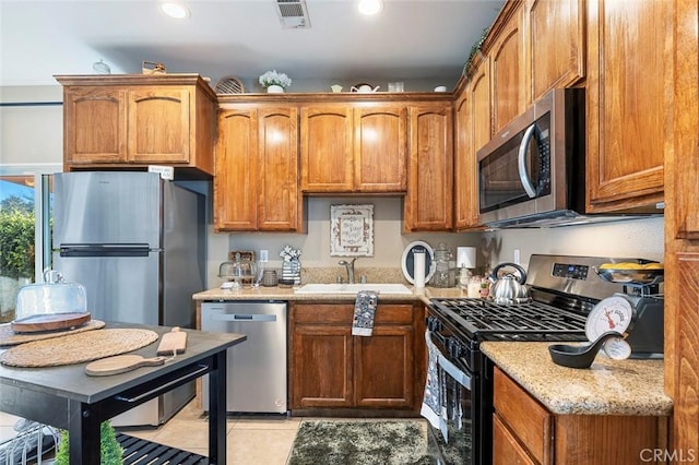 kitchen featuring light stone counters, sink, appliances with stainless steel finishes, and light tile patterned floors