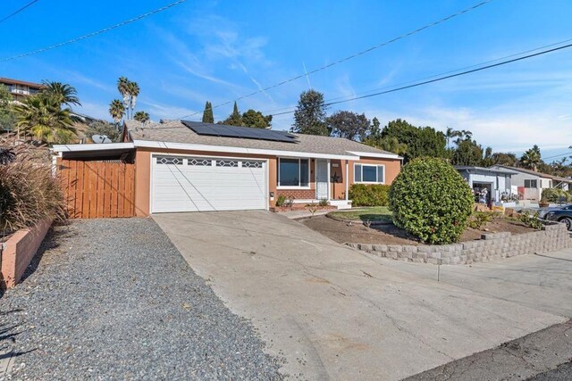 ranch-style house with a garage and solar panels