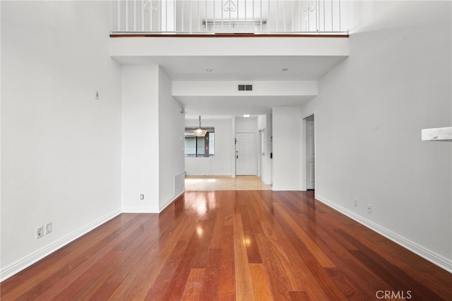 unfurnished living room featuring a towering ceiling and hardwood / wood-style flooring