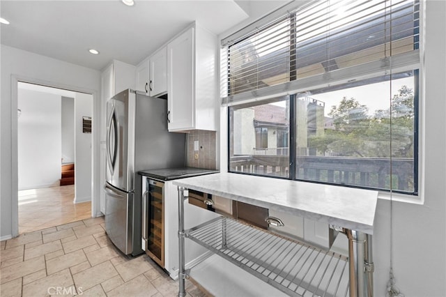 kitchen featuring decorative backsplash, stainless steel fridge, and white cabinets