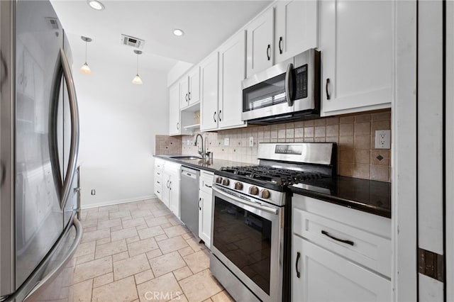 kitchen with appliances with stainless steel finishes, white cabinetry, sink, backsplash, and hanging light fixtures