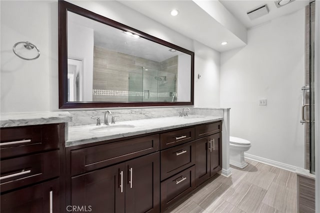 bathroom featuring a shower with shower door, vanity, and toilet