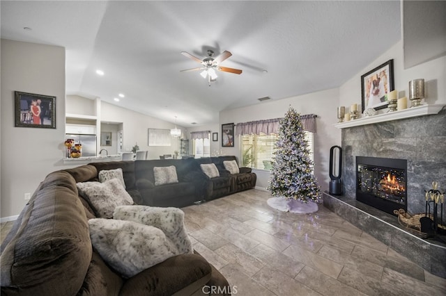 living room featuring ceiling fan, sink, a high end fireplace, and vaulted ceiling