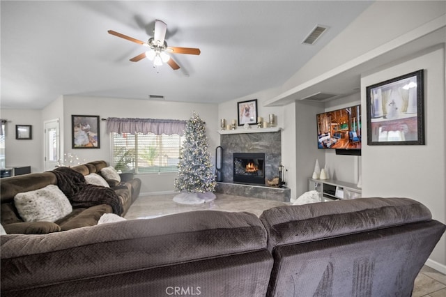 tiled living room with ceiling fan, lofted ceiling, and a premium fireplace