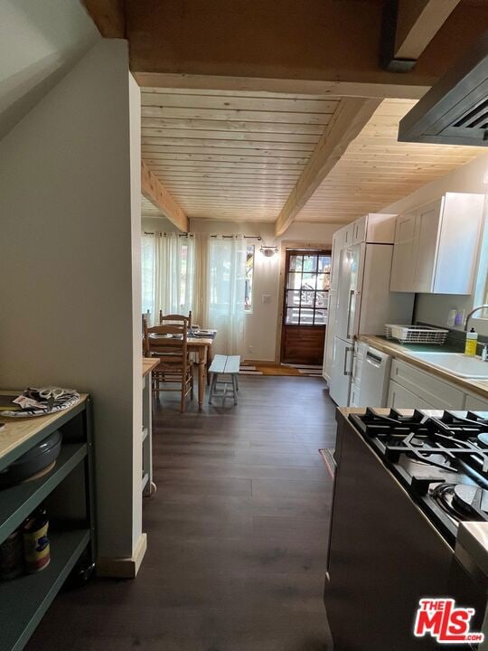 kitchen with dark hardwood / wood-style floors, beamed ceiling, white cabinetry, gas range, and wooden ceiling