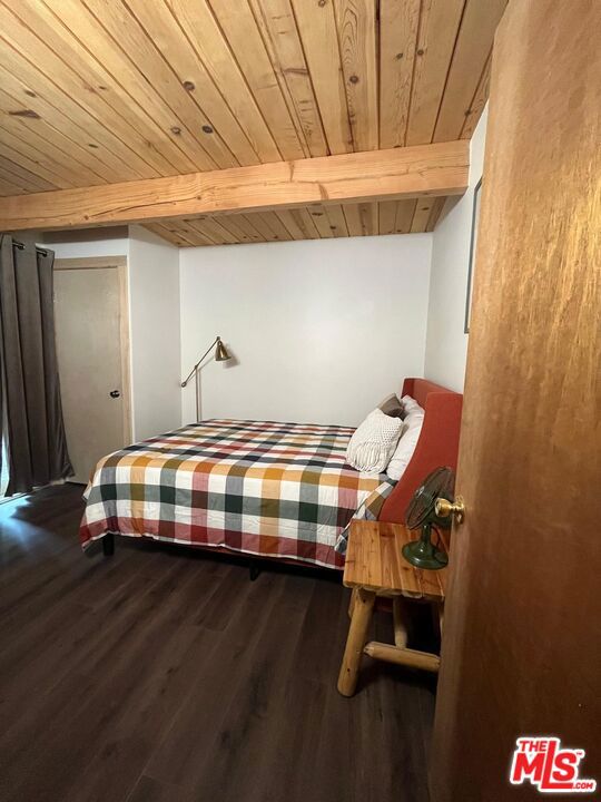 bedroom with beam ceiling, wood ceiling, and hardwood / wood-style flooring