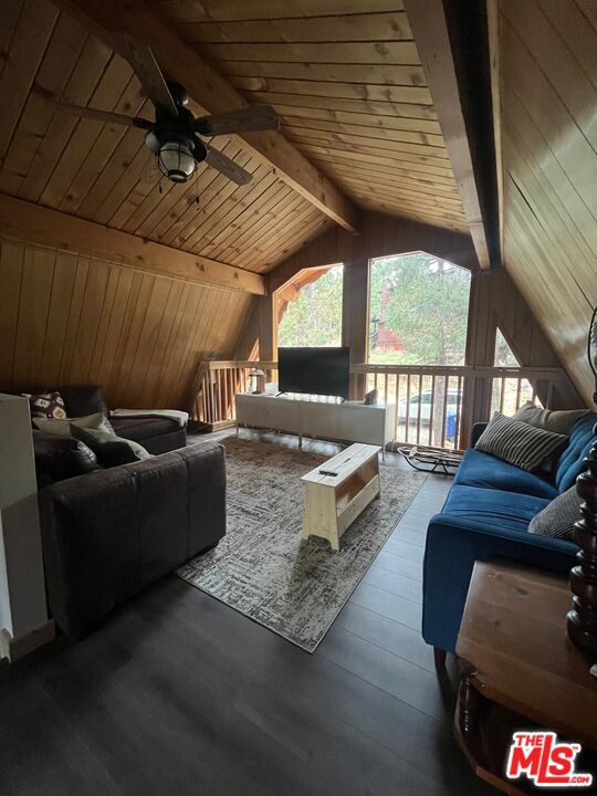 home theater room with wood ceiling, wooden walls, ceiling fan, dark hardwood / wood-style floors, and vaulted ceiling with beams