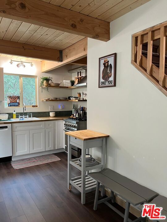 kitchen featuring wood ceiling, white dishwasher, high end range, beam ceiling, and white cabinets