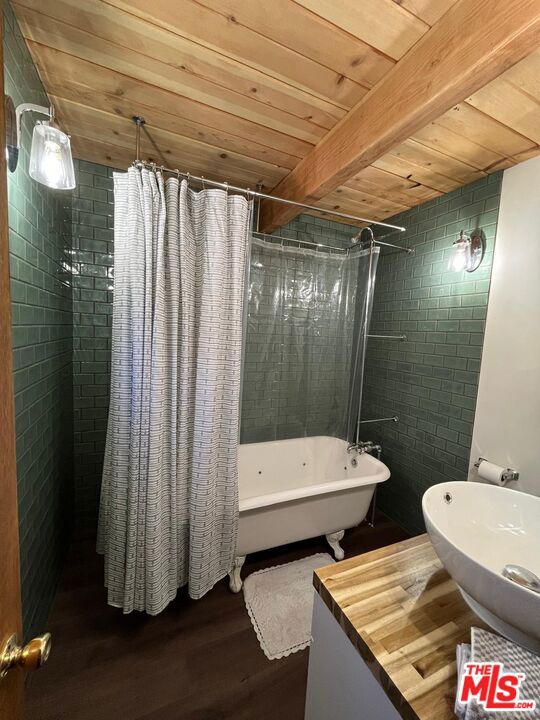 bathroom with hardwood / wood-style flooring, wooden ceiling, beam ceiling, and shower / bath combination with curtain