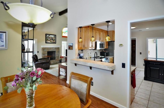 dining space with lofted ceiling with beams, a fireplace, and light tile patterned flooring