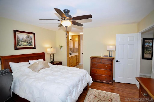 bedroom with ceiling fan, ensuite bath, and dark hardwood / wood-style flooring