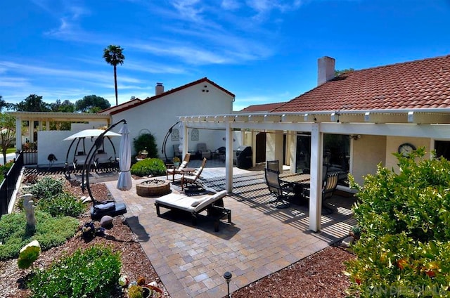 rear view of property with a pergola, a patio area, and a fire pit