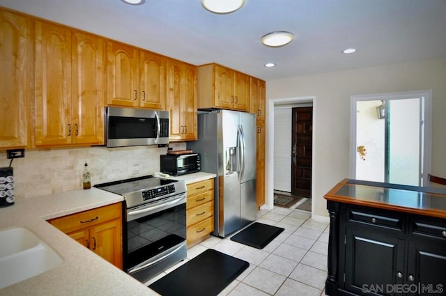 kitchen featuring light tile patterned floors, backsplash, appliances with stainless steel finishes, and sink