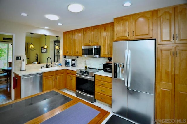 kitchen with stainless steel appliances, decorative backsplash, light tile patterned flooring, hanging light fixtures, and sink