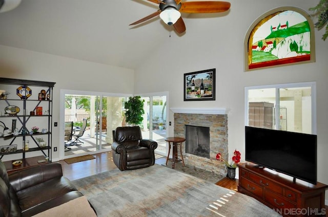 living room featuring ceiling fan, wood-type flooring, a fireplace, and high vaulted ceiling