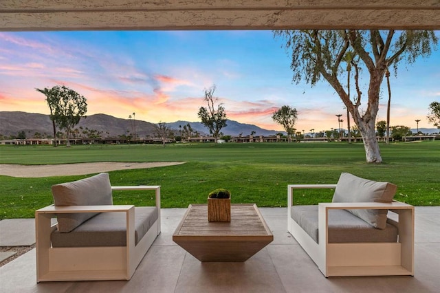 patio terrace at dusk with a mountain view, outdoor lounge area, and a yard