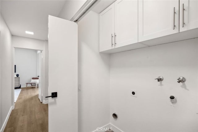 clothes washing area with hookup for an electric dryer, hookup for a gas dryer, hookup for a washing machine, cabinets, and light hardwood / wood-style flooring