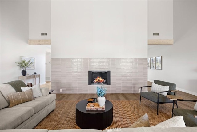 living room with a fireplace, a towering ceiling, and hardwood / wood-style floors