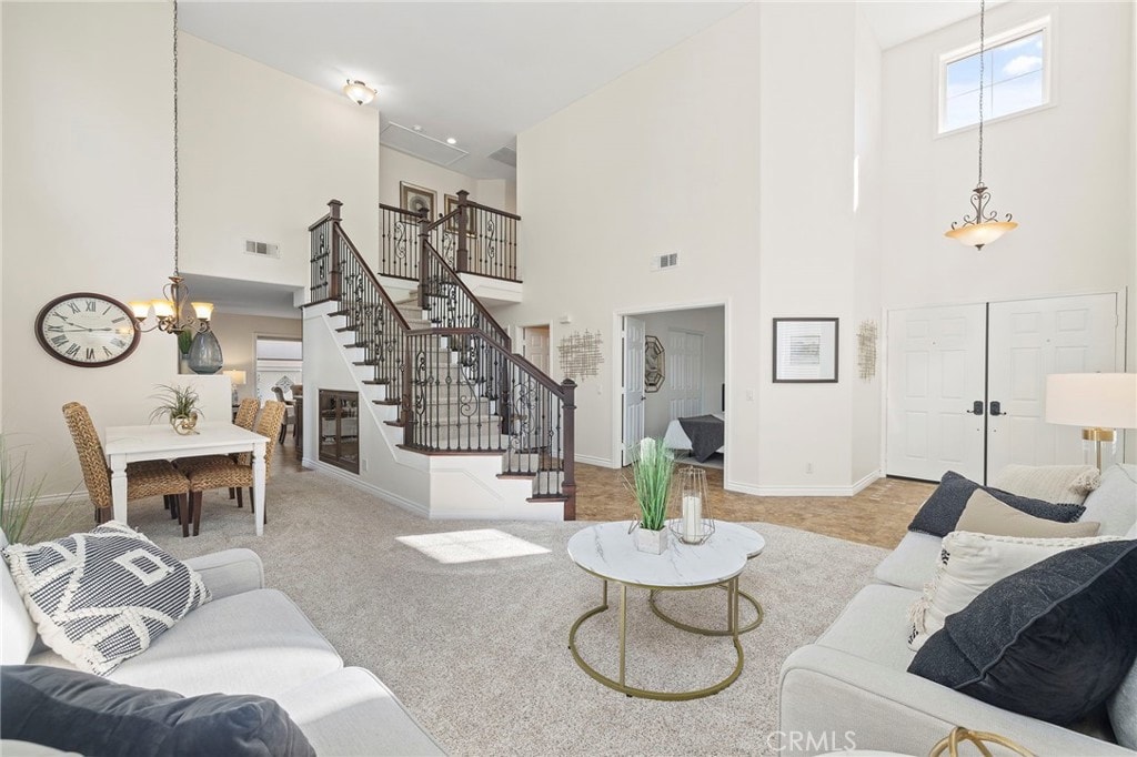 carpeted living room featuring a high ceiling and a notable chandelier