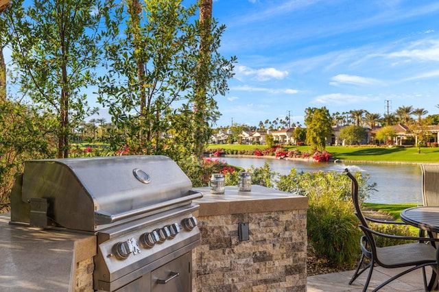 view of patio with exterior kitchen, grilling area, and a water view