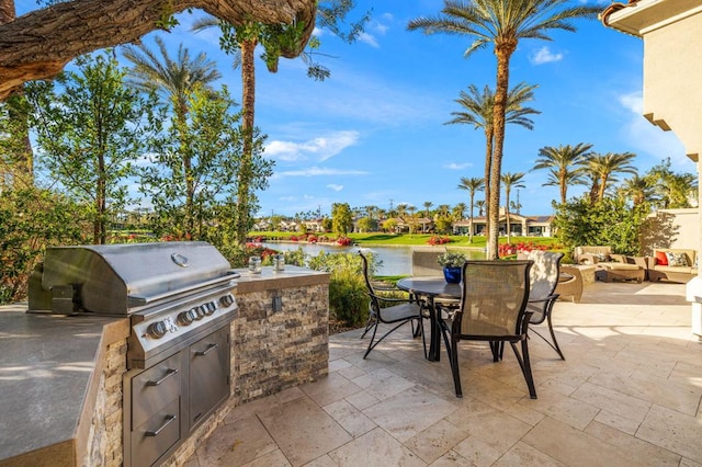 view of patio featuring a water view, an outdoor kitchen, an outdoor hangout area, and a grill