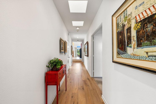 hallway with hardwood / wood-style floors and a skylight