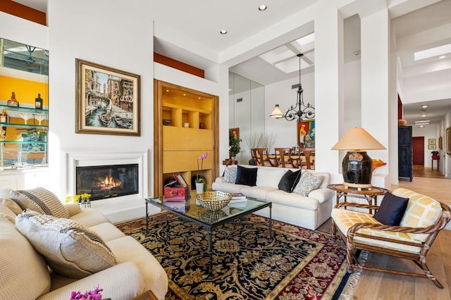 living room featuring a chandelier, wood-type flooring, and built in shelves