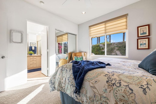 carpeted bedroom with a closet, ceiling fan, and ensuite bath