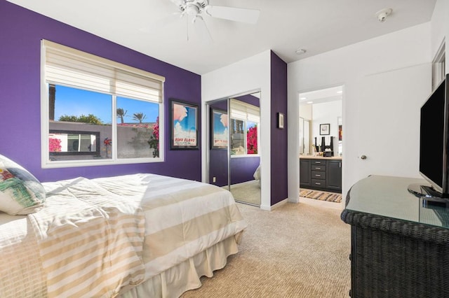 carpeted bedroom with ceiling fan, a closet, and ensuite bath