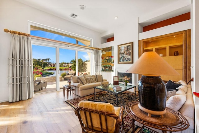 living room with light hardwood / wood-style floors and a water view