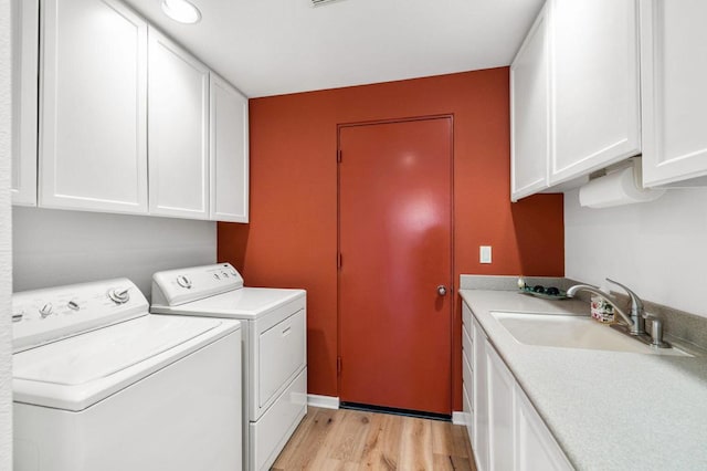 clothes washing area featuring cabinets, sink, light hardwood / wood-style flooring, and washing machine and dryer