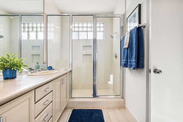 bathroom with a healthy amount of sunlight, a shower with door, vanity, and tile patterned floors