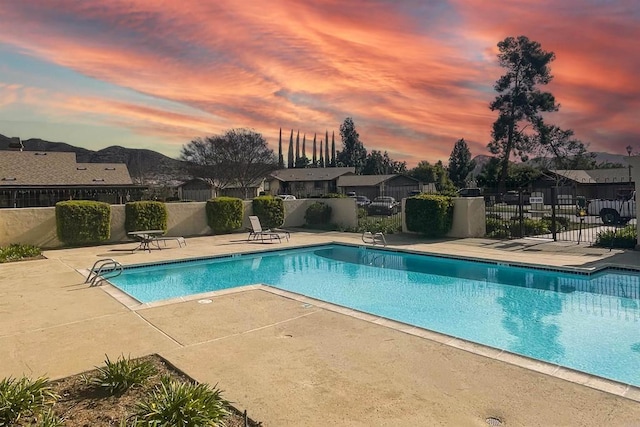 pool at dusk featuring a patio area