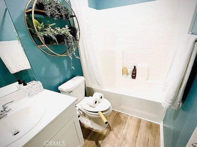 full bathroom featuring toilet, vanity, shower / bath combo with shower curtain, and hardwood / wood-style floors