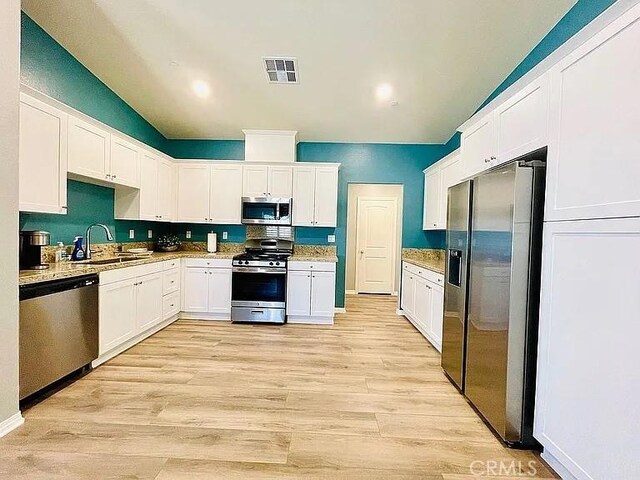 kitchen with light hardwood / wood-style floors, sink, white cabinets, and stainless steel appliances