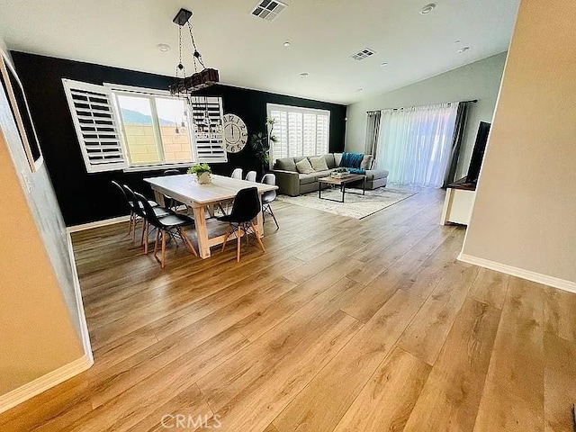 dining room with vaulted ceiling and light hardwood / wood-style flooring