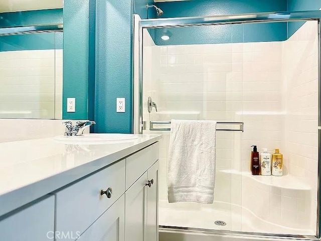 bathroom with a shower with shower door and vanity