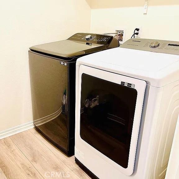 laundry area with light hardwood / wood-style flooring and washing machine and dryer