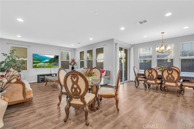 dining area featuring light wood-type flooring and a notable chandelier