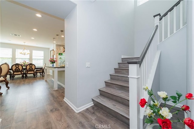 stairs featuring an inviting chandelier and wood-type flooring