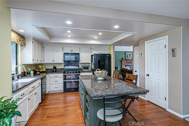 kitchen with white cabinets, a raised ceiling, and black appliances