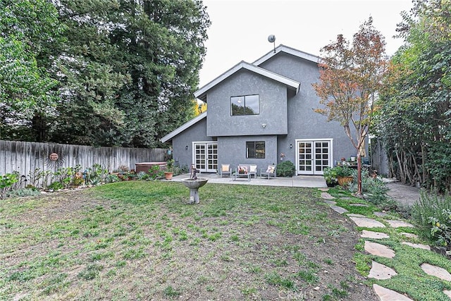 rear view of property featuring a patio area, a jacuzzi, a lawn, and french doors