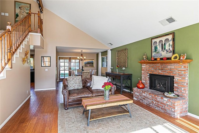 living room featuring a brick fireplace, a chandelier, hardwood / wood-style floors, and high vaulted ceiling