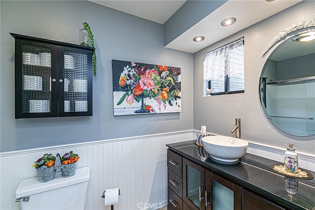 bathroom with toilet, vanity, and a shower with shower door