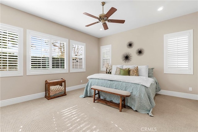 bedroom featuring ceiling fan, light colored carpet, and multiple windows