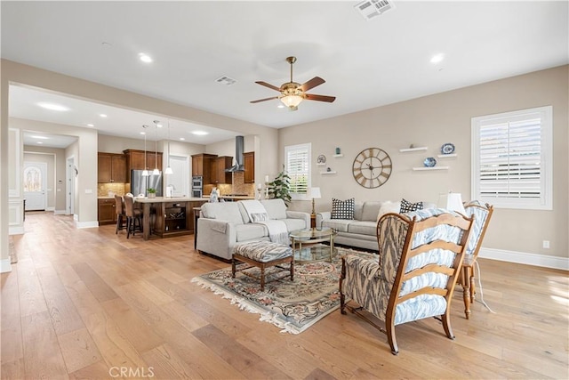 living room featuring ceiling fan, sink, light wood-type flooring, and a wealth of natural light