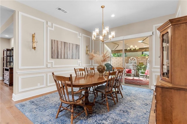 dining room with light hardwood / wood-style floors and a notable chandelier